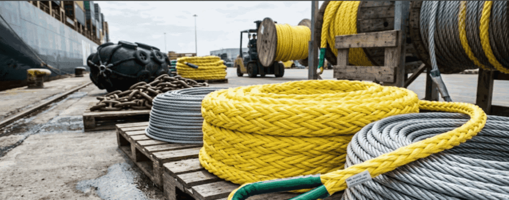 Des cordages d'amarrage tressés robustes enroulés autour d'une borne d'amarrage sur un quai en bois à côté d'un navire amarré